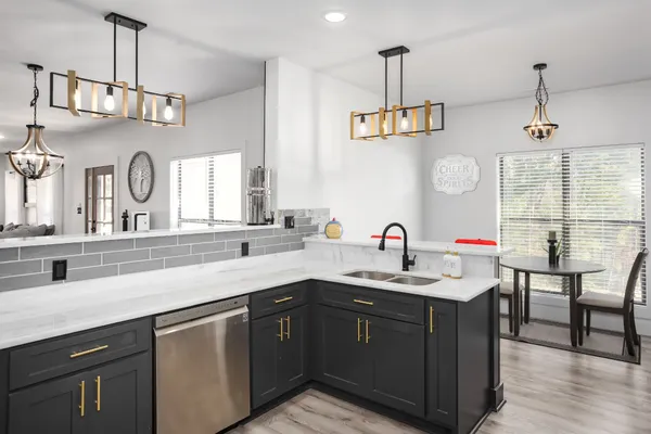 a kitchen with a sink dishwasher a stove and a dining table with wooden floor