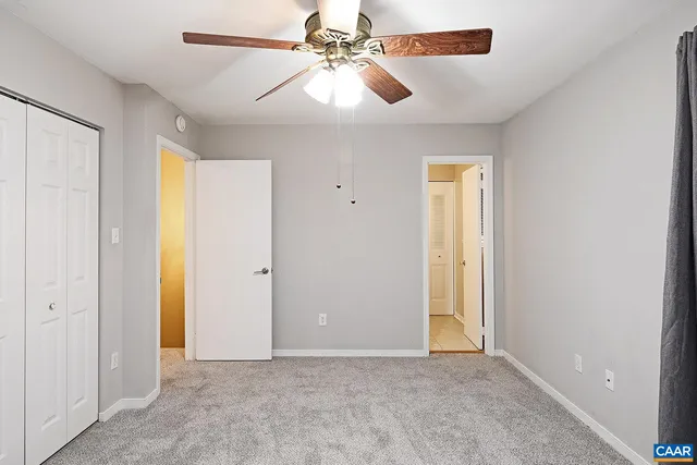 an empty room with closet and a chandelier fan