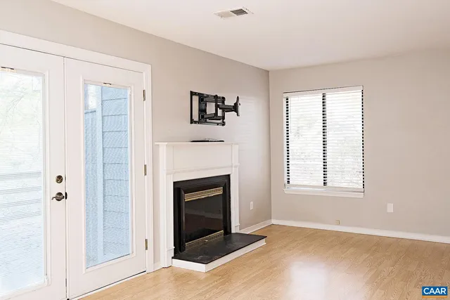 an empty room with windows and fireplace