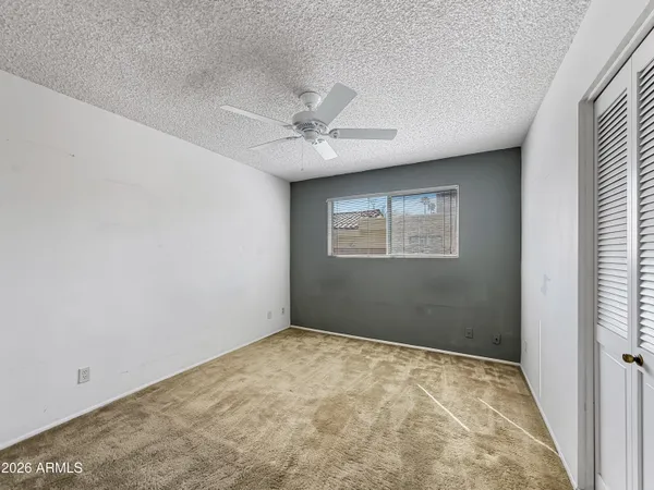 an empty room with a window and a ceiling fan