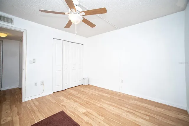 an empty room with wooden floor and fan