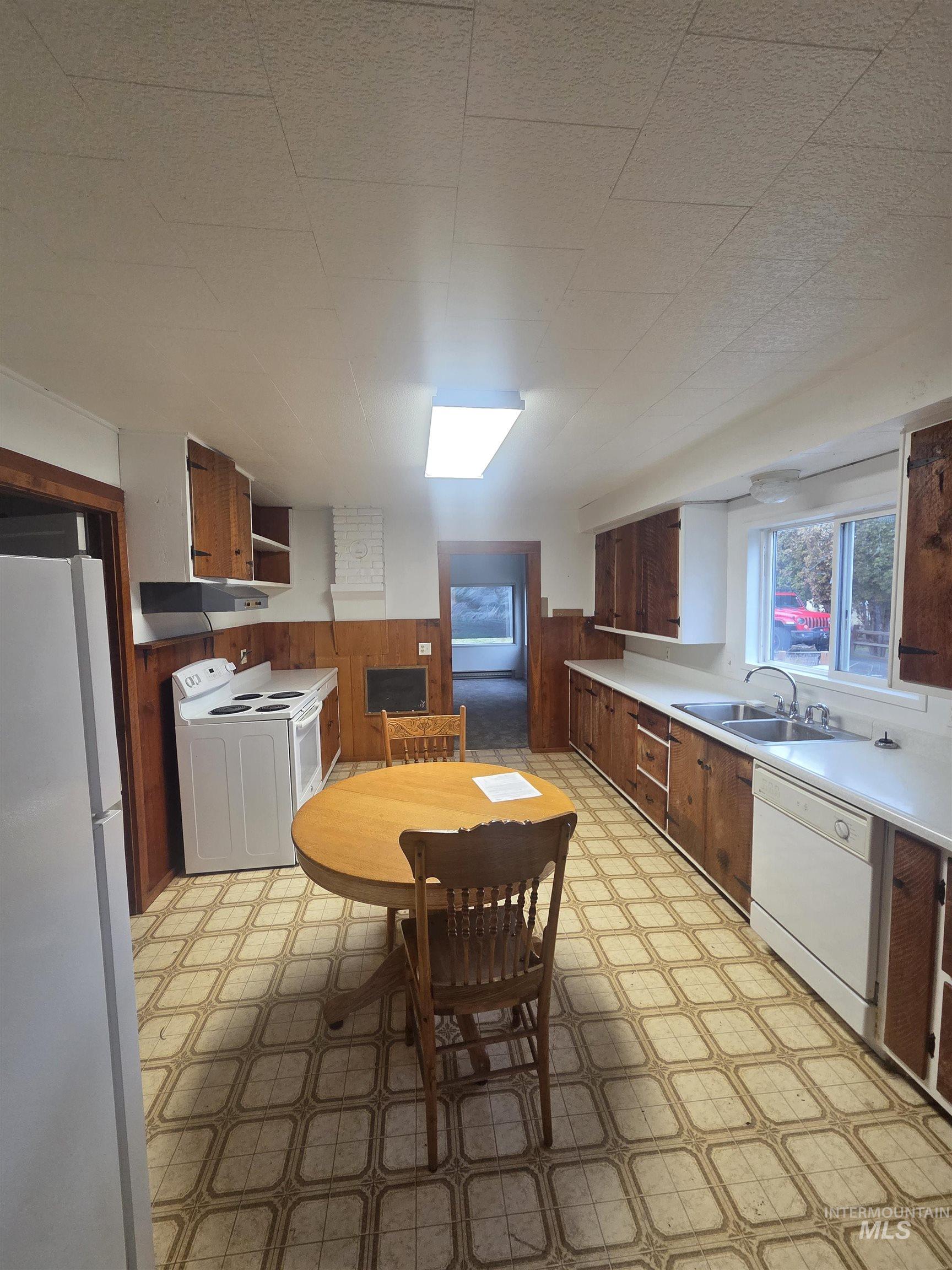 465 South 15th Street Pomeroy, WA 99347 - Photo 11 of 24 Kitchen featuring light floors, white appliances, wainscoting, light countertops, and wooden walls