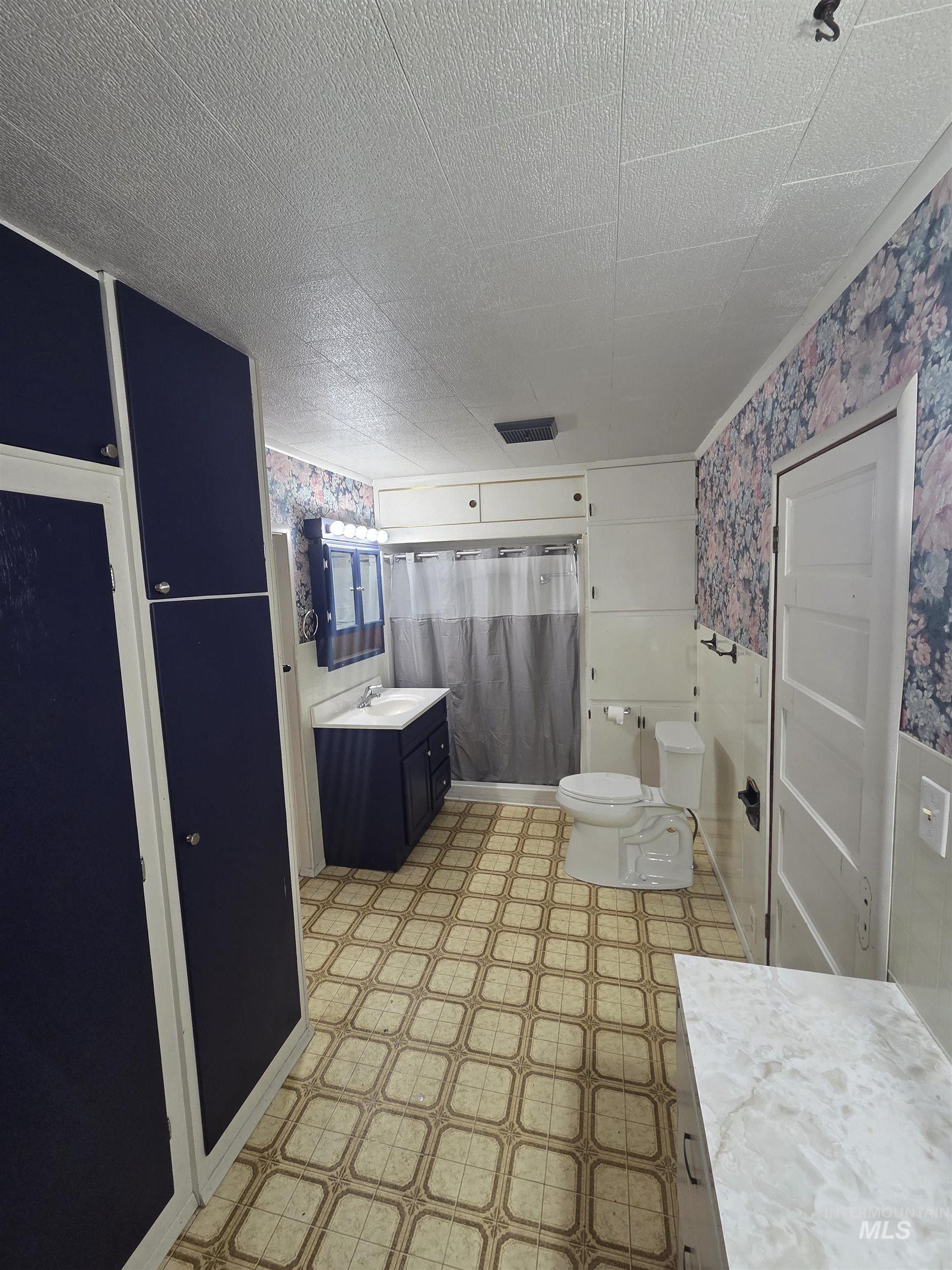 465 South 15th Street Pomeroy, WA 99347 - Photo 21 of 24 Bathroom with light flooring, curtained shower, wallpapered walls, and vanity