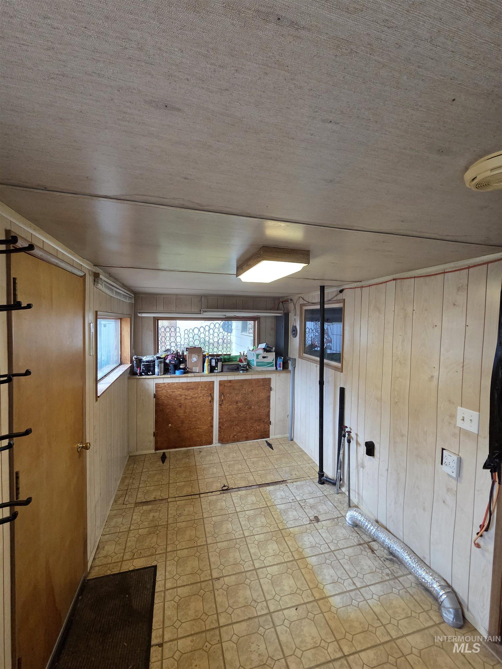 465 South 15th Street Pomeroy, WA 99347 - Photo 8 of 24 Kitchen with wooden walls, light flooring, brown cabinets, light countertops, and a textured ceiling