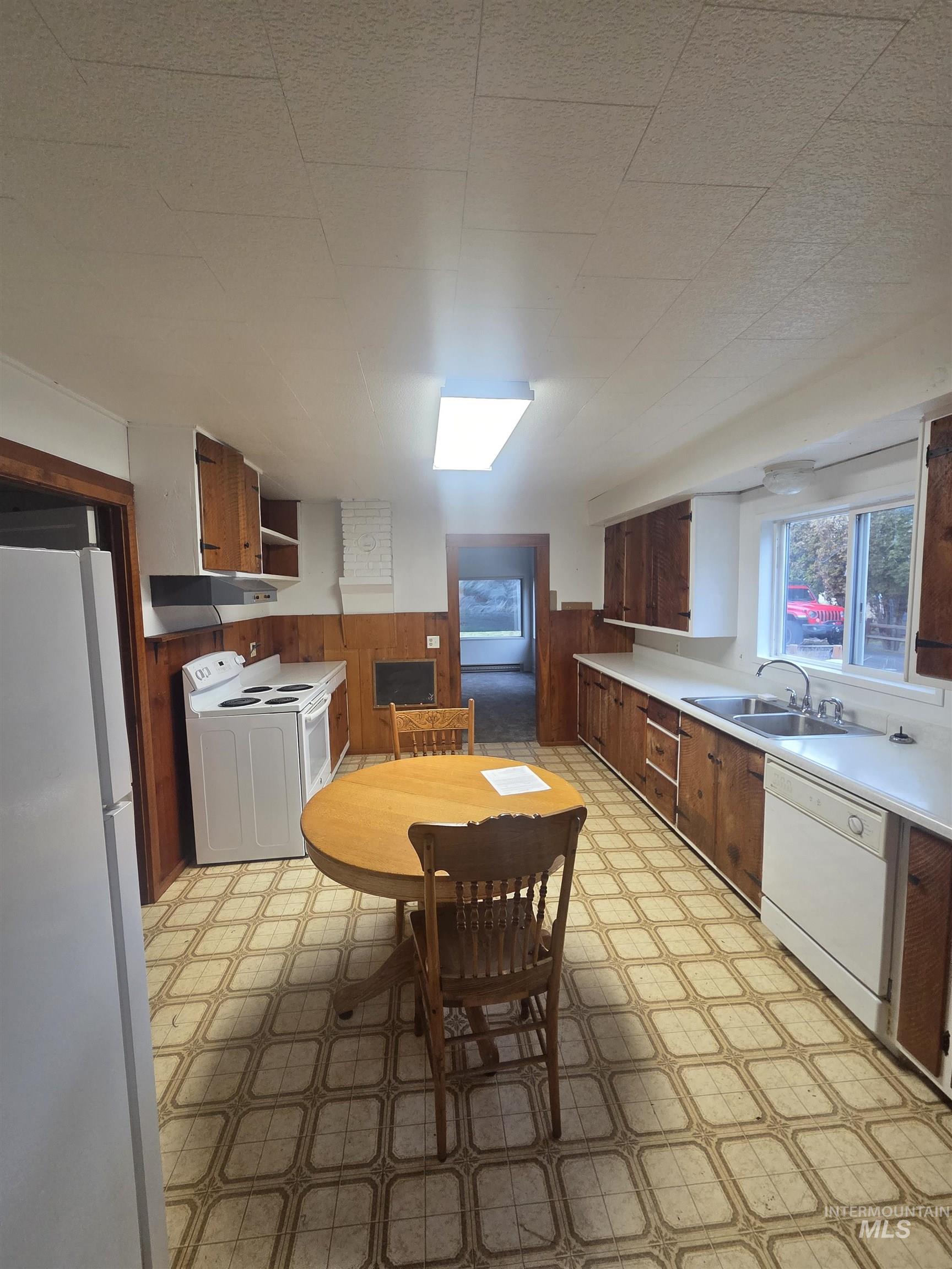 465 South 15th Street Pomeroy, WA 99347 - Photo 9 of 24 Kitchen with light floors, white appliances, a wainscoted wall, wood walls, and light countertops