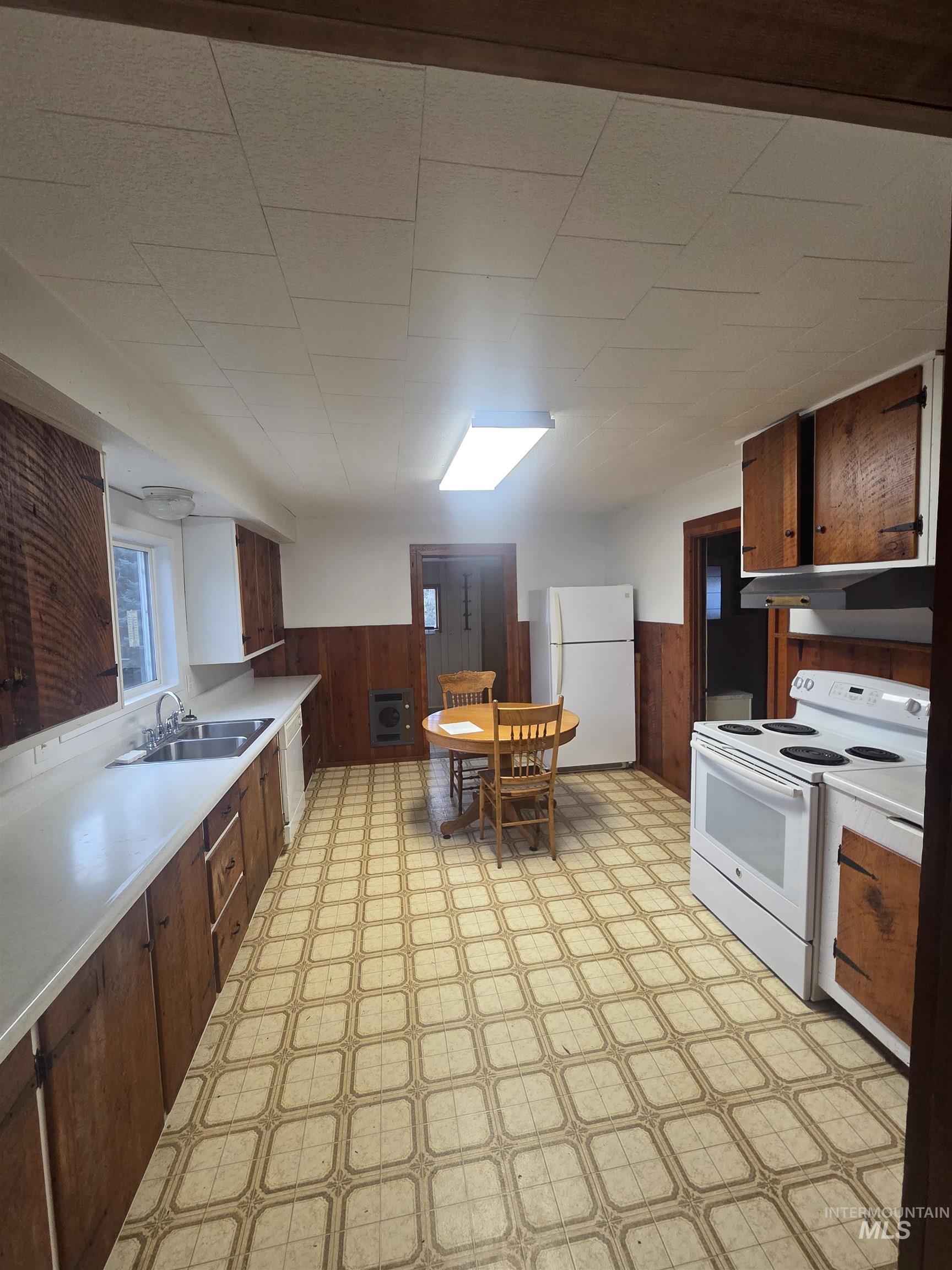 465 South 15th Street Pomeroy, WA 99347 - Photo 10 of 24 Kitchen with light floors, a wainscoted wall, wooden walls, white appliances, and light countertops