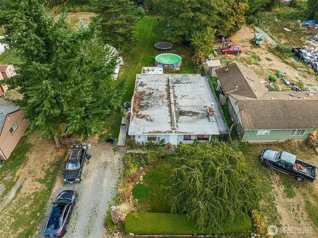 a backyard of a house with lots of potted plants and large trees