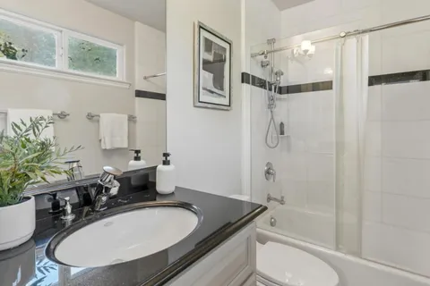 a bathroom with a granite countertop sink toilet a mirror a shower and a bathtub