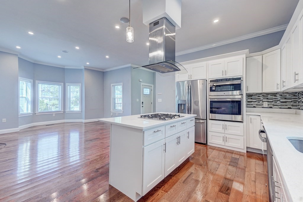 a large kitchen with stainless steel appliances granite countertop a stove and a wooden floors