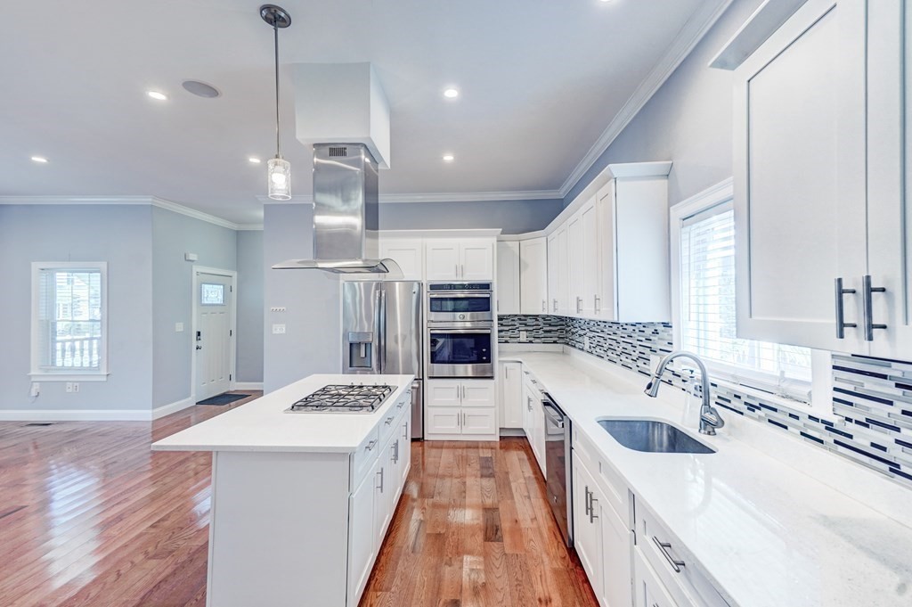 1008-1010 River Street, Unit 1 Boston, MA 02136 - Photo 11 of 29 a large kitchen with kitchen island a stove a sink a center island and wooden floor