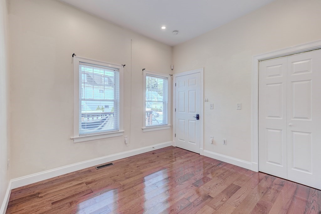 1008-1010 River Street, Unit 1 Boston, MA 02136 - Photo 26 of 29 an empty room with wooden floor and windows