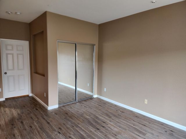a view of an empty room with wooden floor and closet