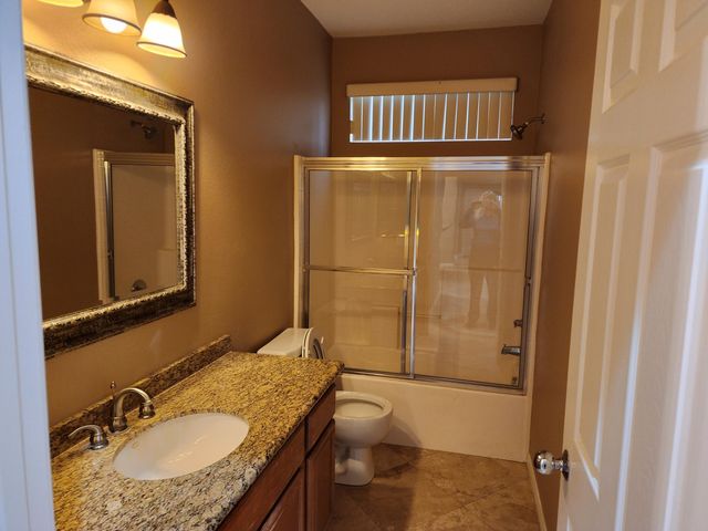 a bathroom with a granite countertop sink toilet and shower