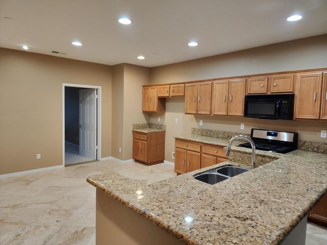 a kitchen with stainless steel appliances granite countertop a sink a stove and microwave