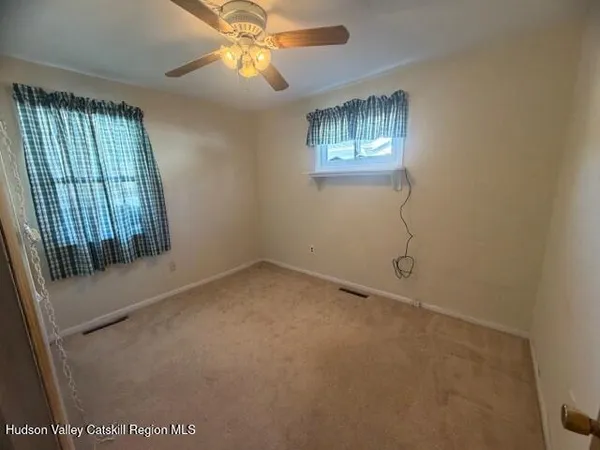 en empty room with windows and ceiling fan