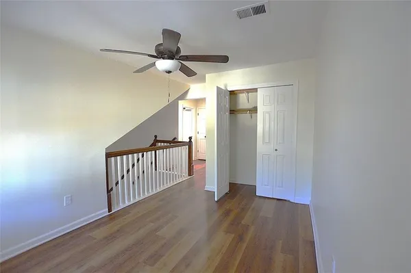 a view of a hallway with wooden floor and a chandelier fan