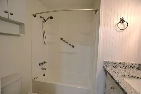 a bathroom with a granite countertop sink a toilet and a shower