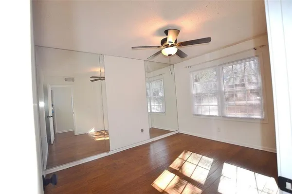 a view of empty room with wooden floor and fan