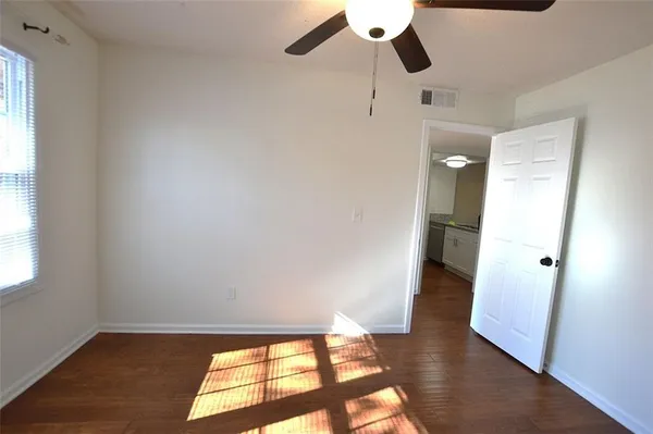 an empty room with wooden floor cabinet and windows