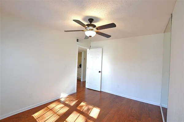 a view of a big room with wooden floor and a chandelier fan