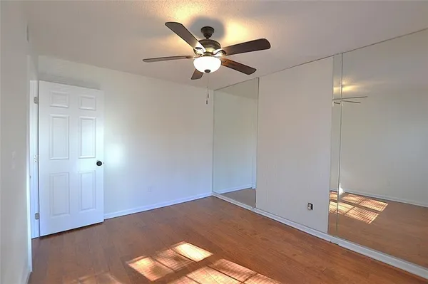 an empty room with wooden floor and ceiling fan