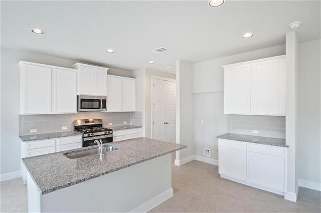 113 Gaida Loop Georgetown, TX 78628 - Photo 12 of 23 Kitchen with white cabinets, light stone countertops, appliances with stainless steel finishes, backsplash, and recessed lighting