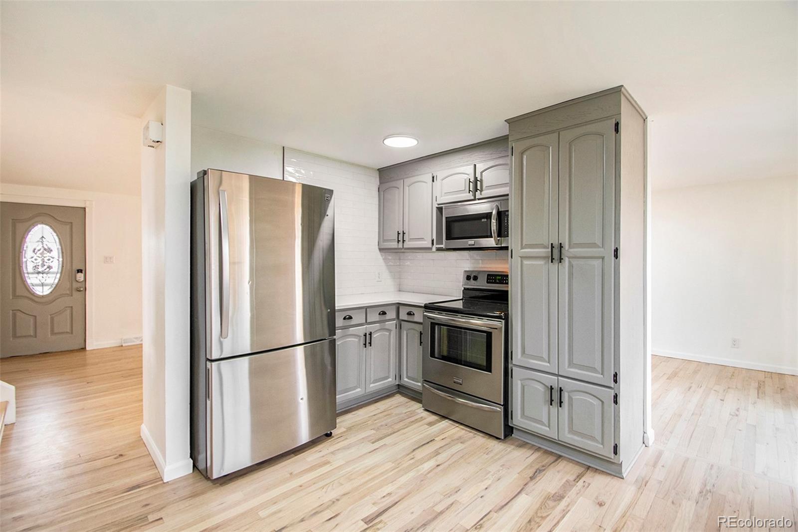 8360 Emerson Street Denver, CO 80229 - Photo 4 of 13 a kitchen with wooden floors and stainless steel appliances