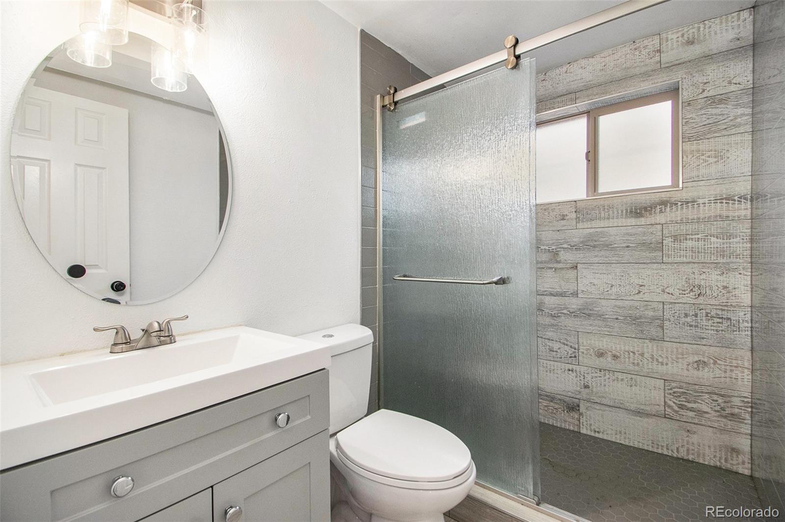 8360 Emerson Street Denver, CO 80229 - Photo 8 of 13 a bathroom with a sink a mirror a toilet and shower