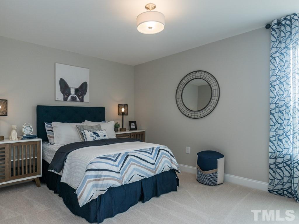 104 Red Cardinal Way Angier, NC 27501 - Photo 24 of 26 a bedroom with a bed and a chandelier