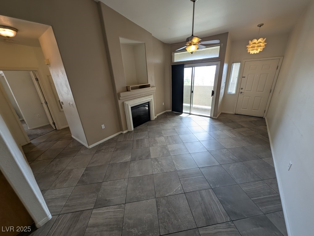 3504 Desert Cliff Street, Unit 203 Las Vegas, NV 89129 - Photo 3 of 20 Unfurnished living room featuring a glass covered fireplace, baseboards, and ceiling fan