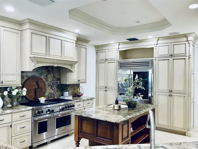 a kitchen with stainless steel appliances granite countertop a stove a sink and white cabinets