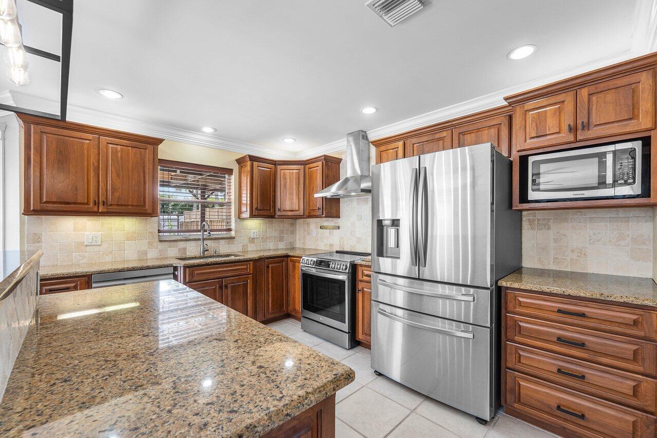 9434 Fox Trot Lane Boca Raton, FL 33496 - Photo 15 of 66 a kitchen with granite countertop stainless steel appliances and wooden cabinets