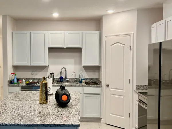 a kitchen with stainless steel appliances granite countertop a refrigerator a stove and white cabinets