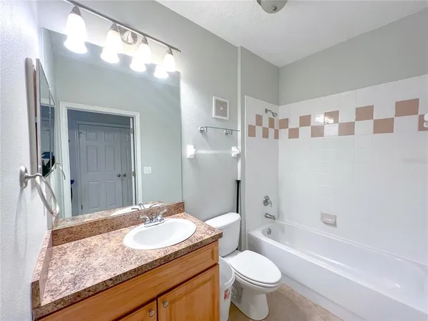 a bathroom with a granite countertop sink a toilet a large mirror and shower