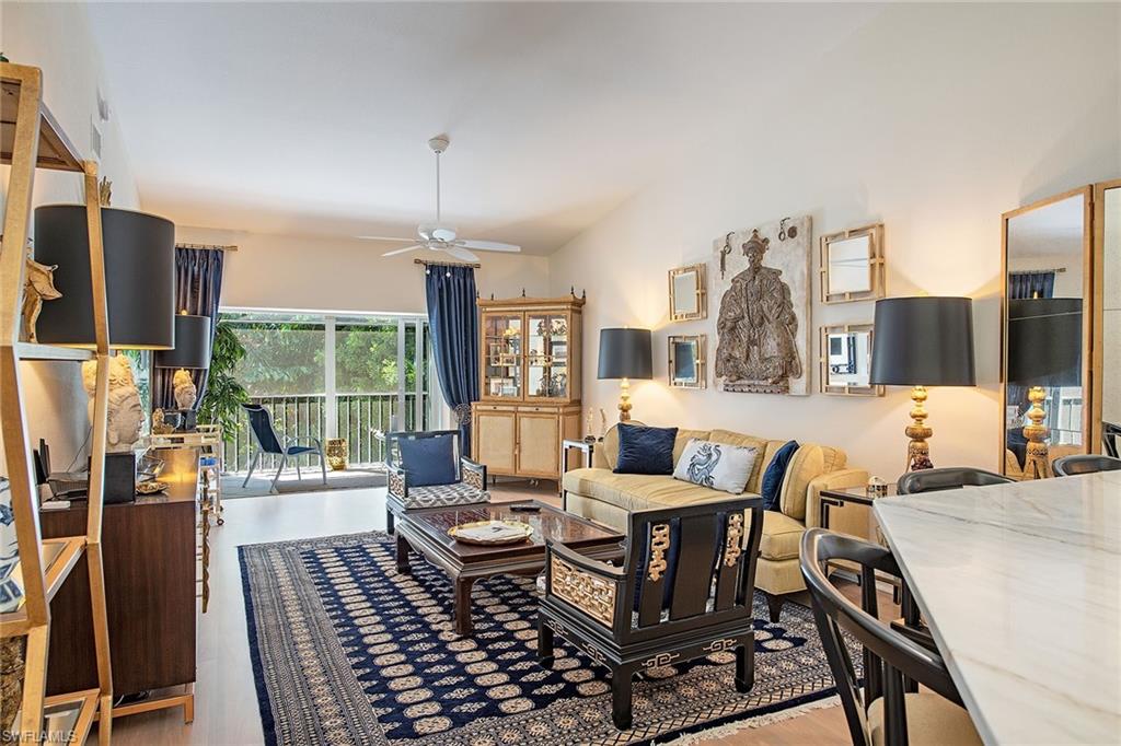841 Tanbark Drive, Unit 202 Naples, FL 34108 - Photo 2 of 12 a living room with furniture a flat screen tv and a floor to ceiling window