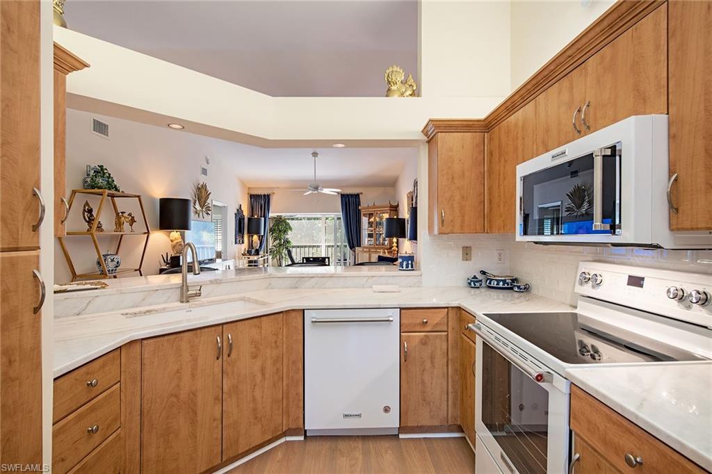 841 Tanbark Drive, Unit 202 Naples, FL 34108 - Photo 3 of 12 a kitchen with a sink stove and cabinets