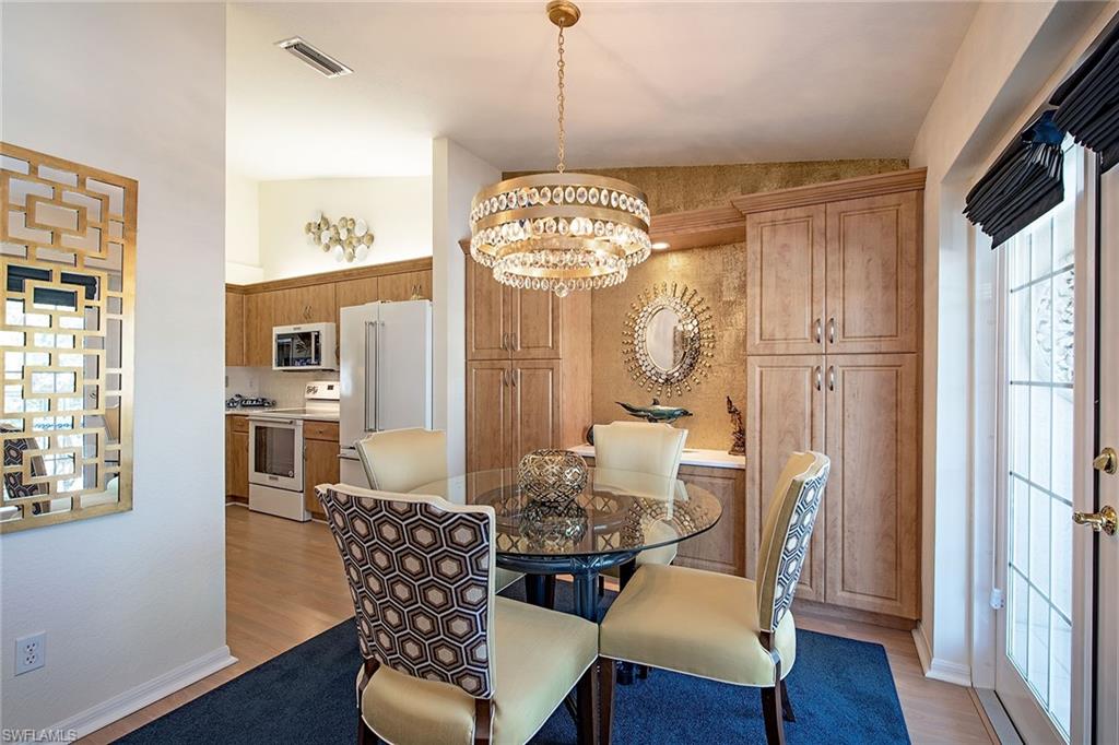 841 Tanbark Drive, Unit 202 Naples, FL 34108 - Photo 4 of 12 a dining room with furniture a chandelier and wooden floor