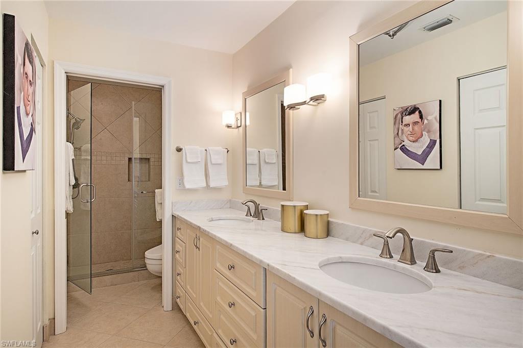 841 Tanbark Drive, Unit 202 Naples, FL 34108 - Photo 6 of 12 a bathroom with double vanity sinks a mirror and a shower