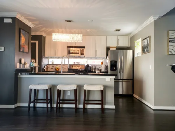 a kitchen with stainless steel appliances granite countertop a refrigerator a stove and a dining table with wooden floor