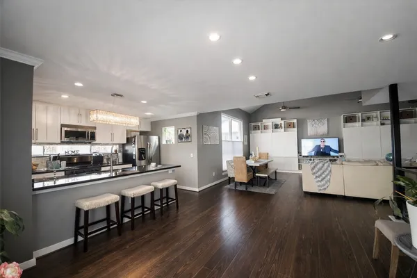 a living room with furniture and kitchen view with wooden floor