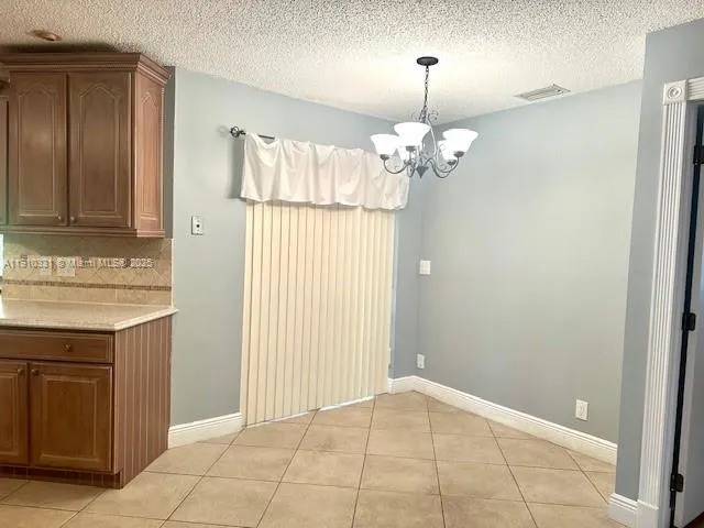a view of a kitchen with granite countertop cabinets and a chandelier