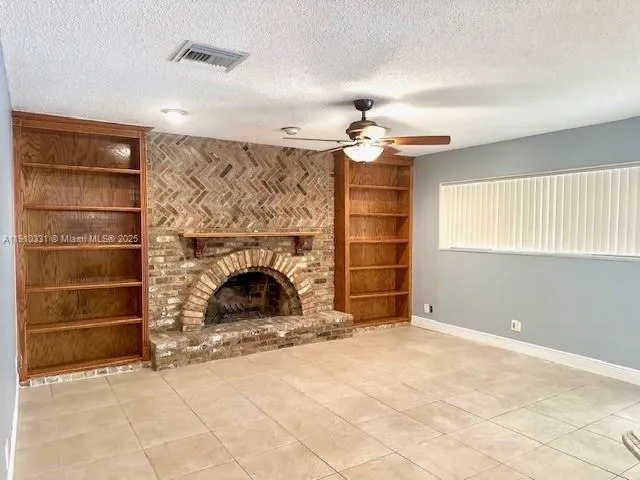 a view of an empty room with a fireplace and a window