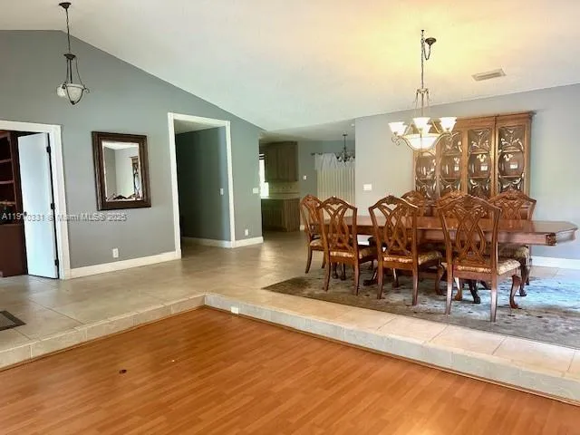 a dining room with wooden floor a chandelier a wooden table and chairs
