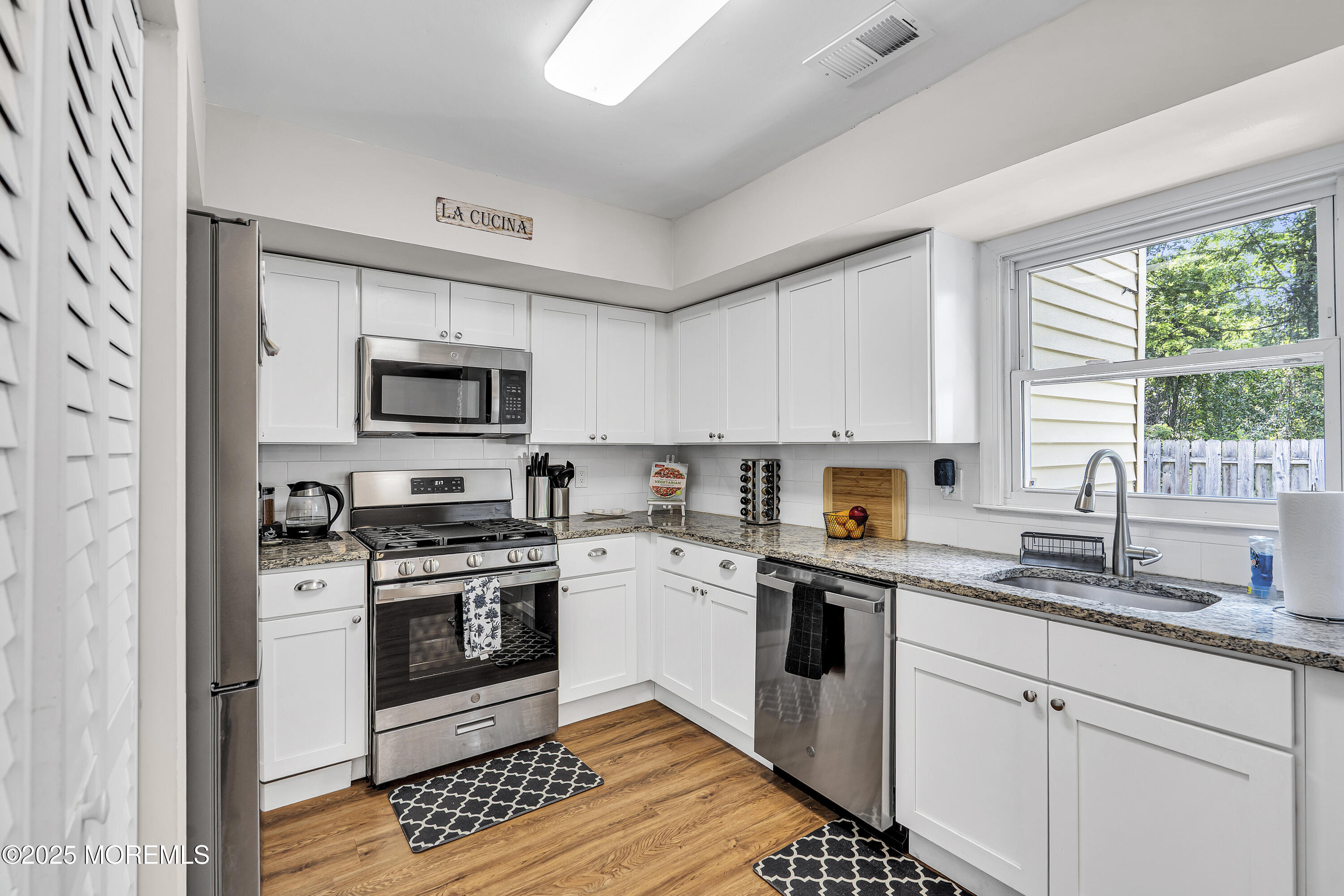 39 Colonial Court Jackson, NJ 08527 - Photo 19 of 26 a kitchen with stainless steel appliances granite countertop a stove a sink dishwasher a refrigerator and a microwave oven with wooden floor