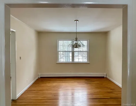 a view of an empty room with window and wooden floor
