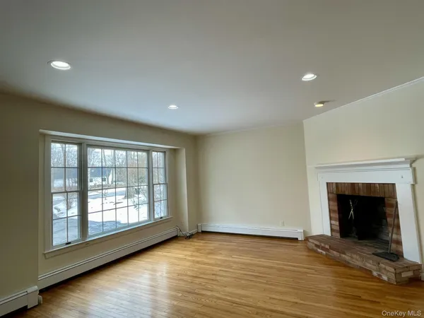 an empty room with wooden floor fireplace and windows