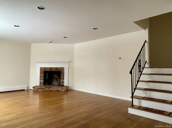 a view of empty room with wooden floor and fireplace
