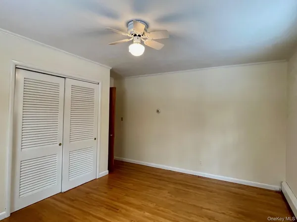 an empty room with wooden floor chandelier fan and windows