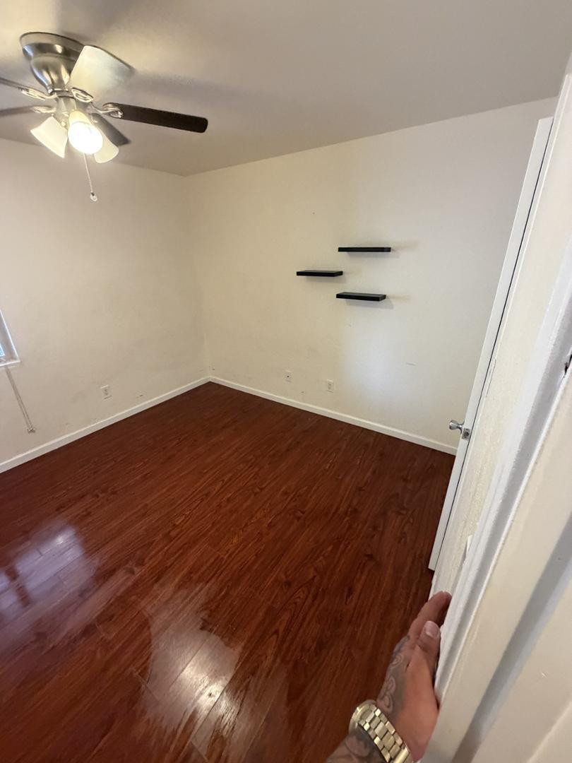 1336 East Mountain View Road, Unit 105 Phoenix, AZ 85020 - Photo 10 of 15 a view of an empty room with a ceiling fan and wooden floor