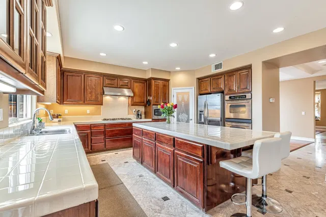 a large kitchen with granite countertop a large counter top stainless steel appliances and cabinets